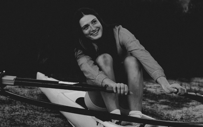 Close up photo of Gen Hart in a speed row boat holding paddles in each hand for the Just Add Venue Campaign